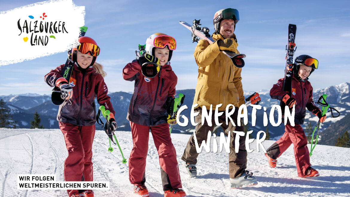 Ein Mann und drei Kinder in Skiausrüstung laufen lächelnd auf einem verschneiten Berghang mit Skiern.
