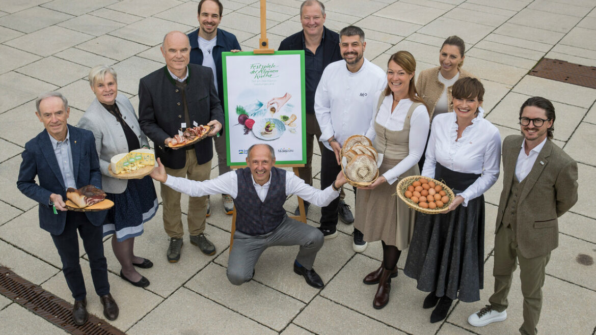 Eine Gruppe von Menschen posiert im Freien mit Körben voller Lebensmittel vor einem Plakat auf einer Staffelei.