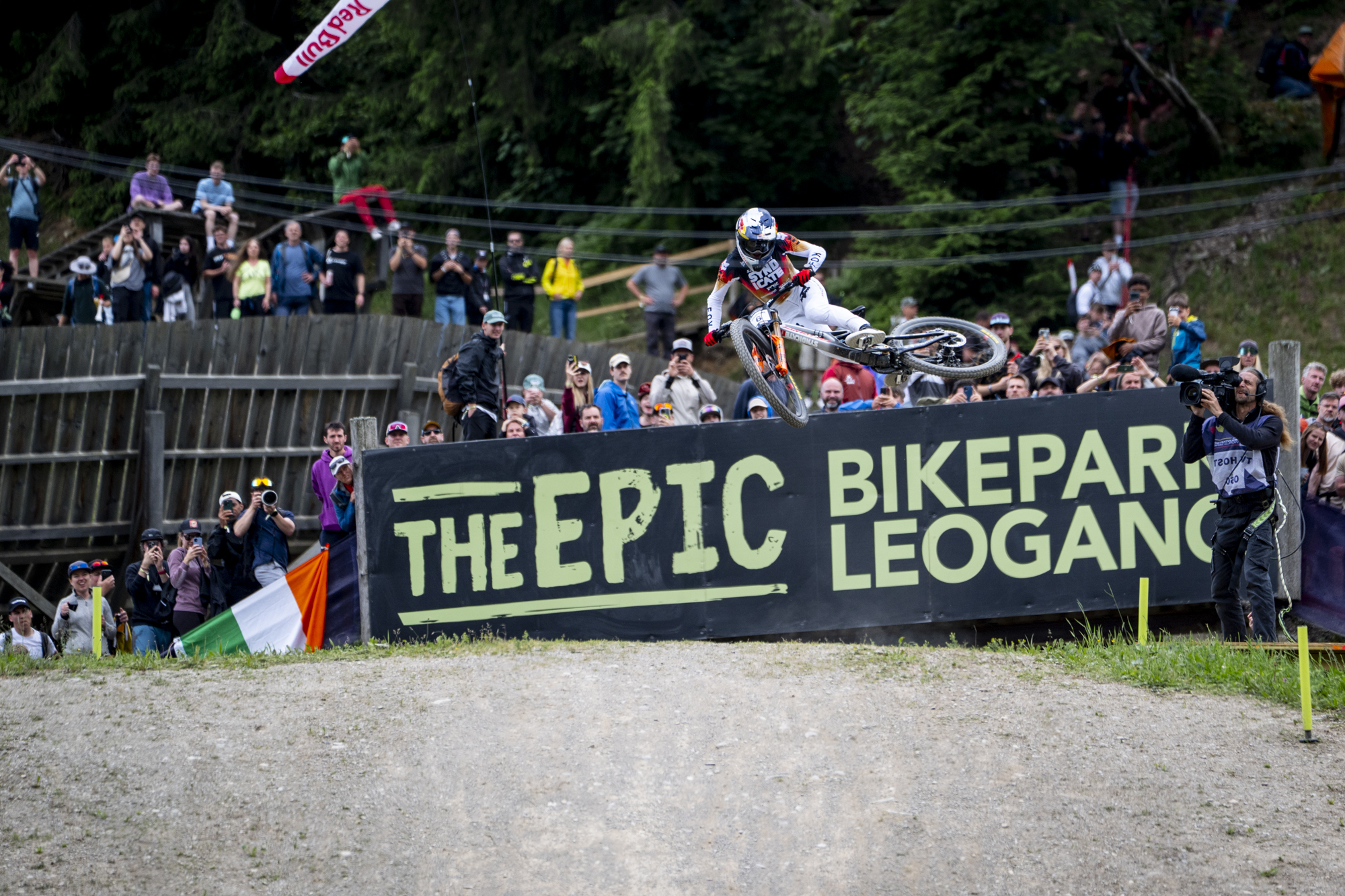 Ein Mountainbiker springt vor einer jubelnden Menschenmenge im Bikepark Leogang, wobei das „THE EPIC“-Schild zu sehen ist.